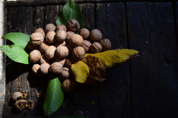 covered yellow and green leaves with walnuts on a wooden table