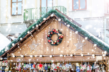 Christmas fair drawing snowfall toned. Part of wooden houses decorated with lanterns in Christmas style the background of the old town.