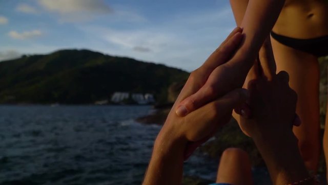 Close-up of the hands of a man and a woman holding each other. Do acro yoga on the beach.