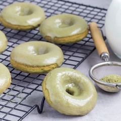 Freshly baked matcha banana donuts with matcha citrus glaze on cooling rack, square format