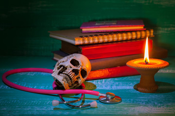 still life human skull on stethoscope and old book with