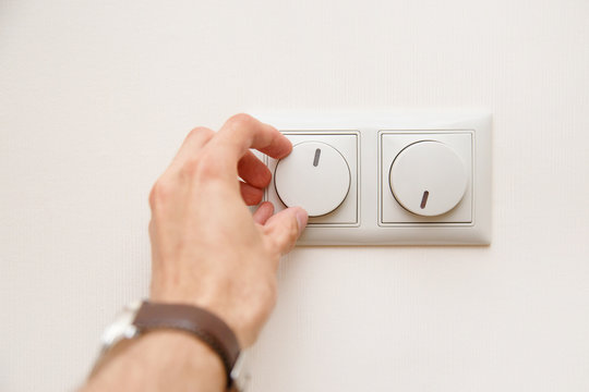 Saving energy concept: Human hand turning down electrical light dimmer switch or conditioner heat controller