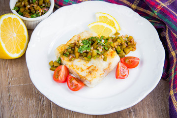 Fried white fish fillet with sauce chutney pickled cucumber, gherkins, onion and parsley, tasty Russian dish