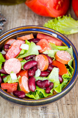 Salad with beans, tomatoes, onion, smoked sausage and lettuce, tasty dish in traditional rustic style