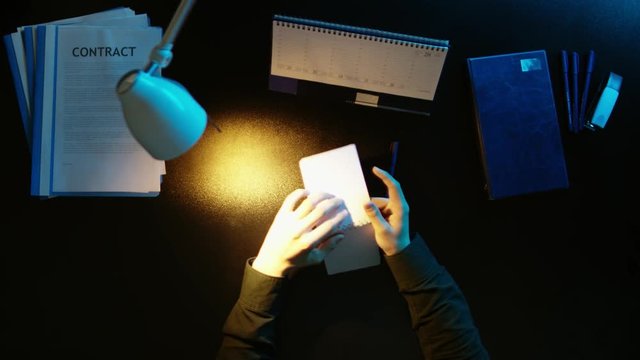 A man is sitting at an office desk and using a phone.