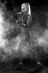 Obraz na płótnie Canvas A strong athletic, woman boxer, boxing at training on the black background. Sport boxing Concept with copy space.