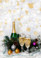 a bottle of champagne and two glasses on the background of fir branches
