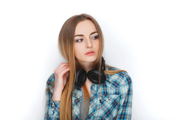 Headshot of a young adorable blonde woman in blue plaid shirt enjoying listening music to big professional dj headphones.