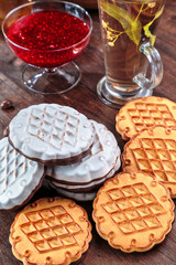 cookies with white chocolate frosting and raspberry jam in a little vase on the table for tea