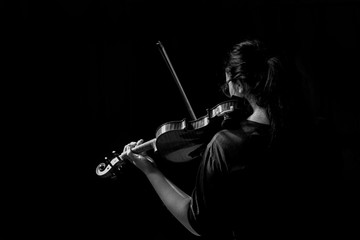 Teenager playing violin back side view.