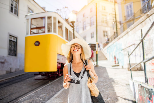 Portrait of a young woman tourist standing near the famous yellow tram traveling in the old town of Lisbon, Portugal