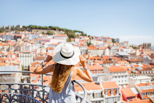 Young woman tourist enjoying beautiful cityscape top view on the old town during the sunny day in Lisbon city, Portugal