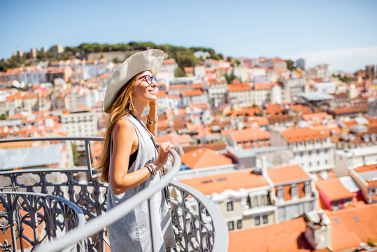 Young woman tourist enjoying beautiful cityscape top view on the old town during the sunny day in Lisbon city, Portugal