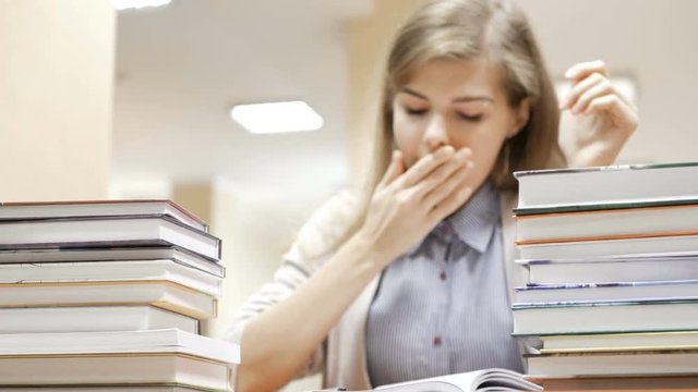 Female student falls asleep after been reading and studying all day in the library