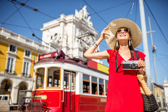 Portrait of a young woman traveler near the red old tourist tram on the Commerce square during the sunny weather in Lisbon city, Portugal