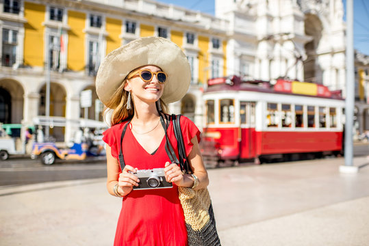 Portrait of a young woman traveler near the red old tourist tram on the Commerce square during the sunny weather in Lisbon city, Portugal