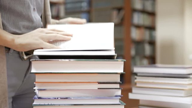 Woman looks through stack of books on the table