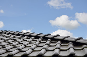 Close up of dark brown ceramic tile roof against blue sky. Copy space