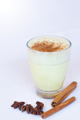 Glass of turmeric latte over white wooden table with copyspace. Turmeric Latte with Nut Milk, cinnamon, honey, ginger