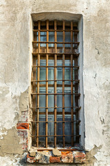 Fototapeta na wymiar Gated window on the wall of an old building