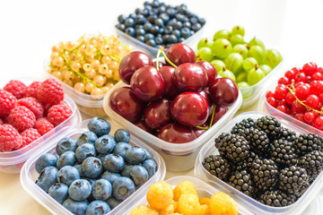 Collage of different fruits and berries isolated on white. Blueberries, cherries, blackberries, grapes, strawberries, currants. Collection of fruits and berries in a bowl. Top view