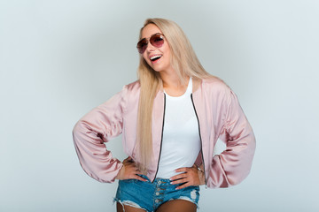 Looking stylish every day! Beautiful young woman with blond hair looking at camera with smile while standing against grey background