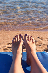 Beautiful woman's legs on the beach sand