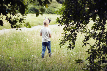 6-year-old boy walking throug a field wearing a paper crown.
