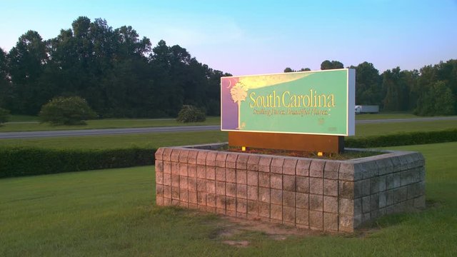 South Carolina Signage at Welcome Center with Passing Vehicle Traffic on Interstate in the Background during Golden Morning Sunrise