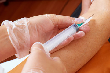 Doctor take needle blood sample.