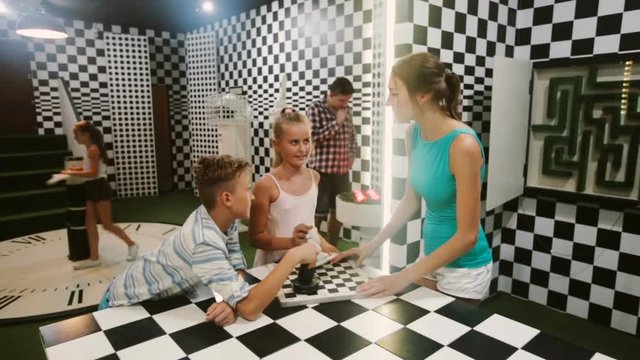 Parents with their children are visiting the escape room stylized under chessboard.
