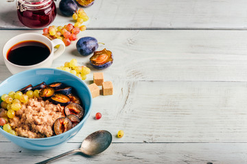 Porridge with plum, grapes and cup of coffee