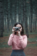 Girl photographer in the woods holds in her hand an old vintage film camera