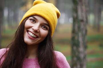 Portrait of a beautiful famous brown girl in a yellow hat and black sexy dress. In the forest near lake. Autumn