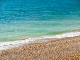 Fototapeta na wymiar Pebble beach and turquoise water of the sea, blue waves, surf