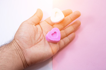 Hands holding two heart-shaped candies