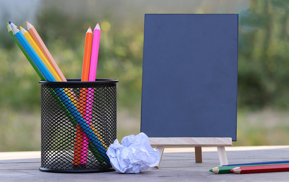 Color pencils in black box with blackboard on wood tripod and wrapped paper. Copy space for design and texture. back to school, Learn concept.
