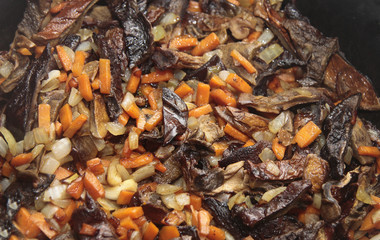 Mushrooms fried on the pan with carrot and onion