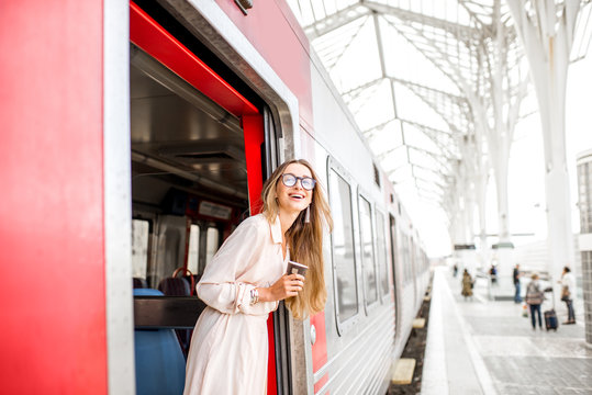 Young and happy woman pulling face out the train door looking for somebody at the railway station