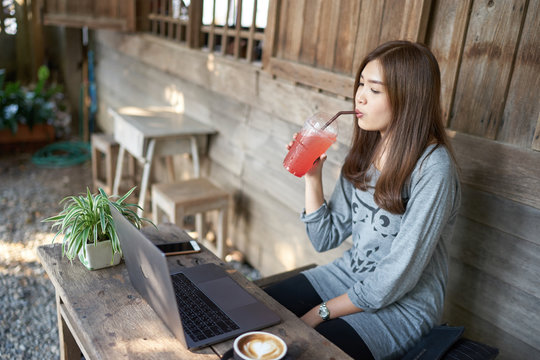 Beautiful Asia Woman Drinking Italian Soda And Using Laptop At The Vintage Coffee Shop