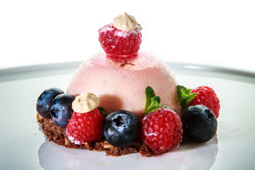 delicious pink dessert covered with fresh raspberries and blueberries