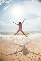 Fototapeta na wymiar A girl is jumping on the ocean shore.
