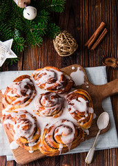 Christmas buns with cinnamon and icing on a wooden background.