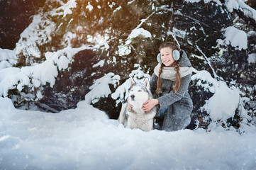 Obraz premium beautiful young girl in a gray coat in winter forest with Siberian Husky. Symbol of new year 2018.