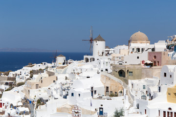 Fototapeta na wymiar Landscape panorama with white houses and ancient wind mill in the Oia city in Greece