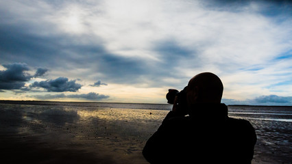 anonymous Passionate photographer shoots the landscape in moody silhouette. © kevin