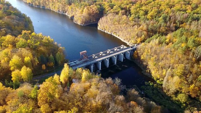 Aerial view of the dam on river with trees covered yellow foliage