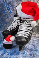 Gordijnen Hockey men's skates and puck close-up with Santa cap, concept of Christmas winter tournaments on a blue background © shintartanya