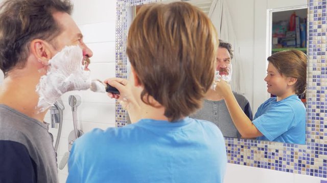 Kid laughing applying shaving cream to dad comedy tracking shot