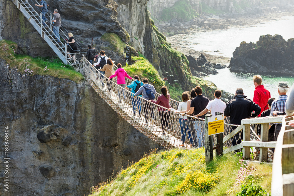 Wall mural thousands of tourists visiting carrick-a-rede rope bridge in county antrim of northern ireland, hang